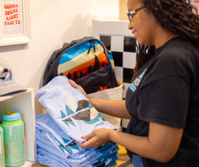 MSP store employee placing a loon t-shirt on display.