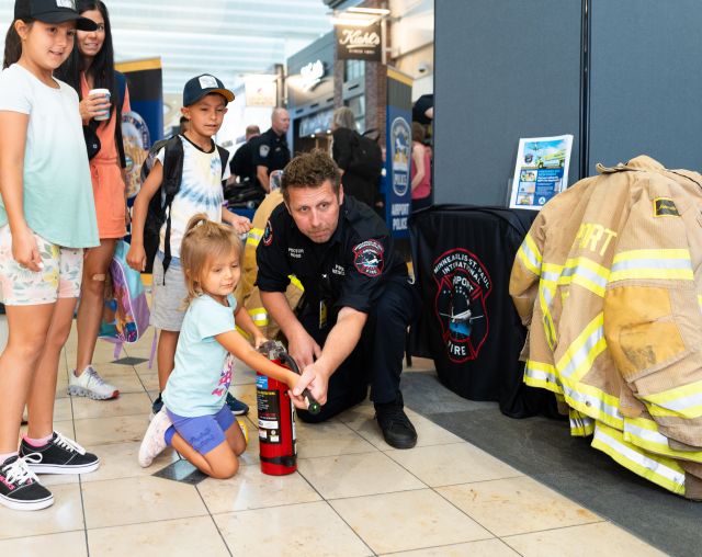 An MSP Airport firefighter shows a young passenger how to use a fire extinguisher